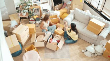 Oturma odasında karton kutuyla oturan mutlu çift kutudan mobilya topluyor. Lezbiyen aşığın yeni bir daireye ya da eve taşınırken konuştuğu en iyi manzara. Kız aşkı. Myrmidon.