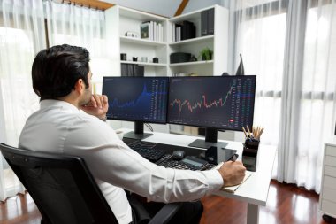 Akıllı tüccar işadamı, modern merkez ofisindeki araştırma pazarında en yüksek kârlı finansal teknolojiye yatırım yaparak bilgisayar üzerinde iki dinamik borsa yatırım ekranını analiz ediyor. Tahmin et..