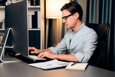 Akıllı iş adamı iş paragrafı dinamik pazarlama analizi planını analiz ediyor. Kağıt kağıtları ve bilgisayar monitörü raporlarını gece evdeki belge verileriyle karşılaştırmak için hazırlıyor. Bireysel.