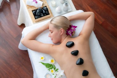 Lüks tatil beldesindeki kaplıca salonunda sıcak taş masajı. Gündüz huzurlu ortam, mutlu kadın müşteri bazalt taşı masajının keyfini çıkarıyor. Sessiz.