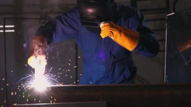 Fabrikada çelik kaynak makinesiyle çalışan metal kaynakçı güvenlik ekipmanı takıyor. El becerisi iş gücü kavramına göre metal imalatı ve inşaat bakım hizmeti.