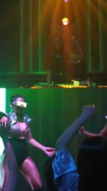Bir grup insan disko gece kulübünde DJ 'in sahnede çaldığı müzikle dans ediyor. Yeni yıl partisi ve gece hayatı konsepti .