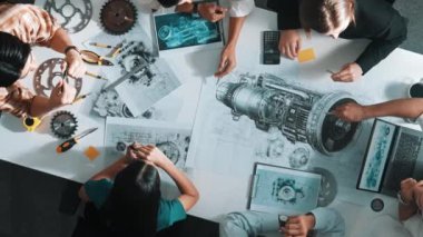 Türbin motoru tasarlamak için çalışan akıllı mühendis takımının yukarıdan aşağıya hava görüntüsü. Profesyonel teknisyen jet motoru yapımını tartışırken motorun bir kısmını işaret ediyor. Hizalama.