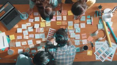 Sıradan giyinen, dizüstü bilgisayara bakan ve fikir paylaşan iş adamlarının en aşağıdan görünüşü. Yöneticinin hava görüntüsü çalışıyor ve masadaki renk paletini istatistiksel grafik hologramıyla kontrol ediyor. Sempozyum.