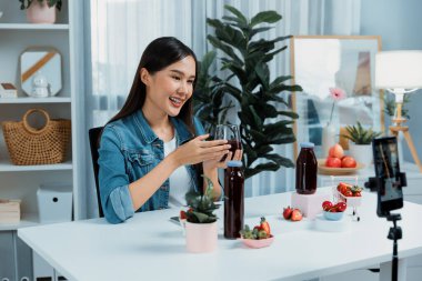 Gülümseyen, güzel Asyalı genç, lezzetli karışık çilek ve kiraz suyu detoksu içeceklerini inceleyen, sosyal medyada özel promosyon satışı için sağlıklı ürünler sergileyen. Taktik.