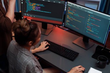 Bilgi teknolojisi modern ofisteki neon ışık odasında iki ekranın bilgisayarında veri çalıştıran akıllı web sitesi geliştirme kodlayıcı sistemi ile tartışan bilişim geliştiricileri. İnfobahn.