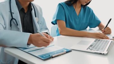 Hastane masasında birlikte çalışan ve tıbbi tedavi planlayan çeşitli profesyonel sağlık görevlileri. Takım çalışması başarılı hastalıklara ve hastalıklara yol açar. Ağır çekim. Katı.