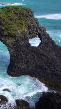 İzlanda, Arnarstapi 'nin Atlantik kıyısındaki inanılmaz taş kemer Gatklettur bazalt kayası. Ünlü doğal yaşam formu İzlanda 'nın batısını ziyaret etmek için turistleri cezbediyor..