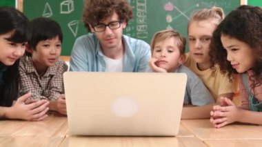 Kafkas öğretmeni ve çeşitli öğrenciler sınıfta dizüstü bilgisayara bakıyor. Kodlama programını öğrenen ya da öğretmenlik yaparken yazılım kullanarak oluşturulan çok kültürlü çocuklar. Pedagoji.