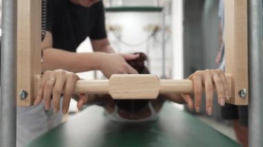 Pilates Cadillac masasında bar tabanlı bir alıştırmada bir müşteriye yardım eden eğitmen. Cadillac 'ta kuğu dalışı yapan kadın beden gücünü ve beden eğitimini arttırıyor. Alışkanlık.