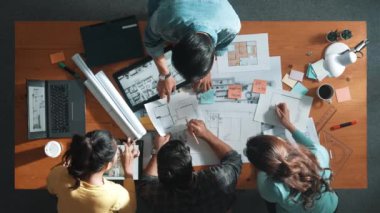 Yöneticinin proje planı yazması ve toplantıda oturması. Bilgisayarlı ve teçhizatlı ev inşaatı hakkında planlar yapan ve paylaşan iş adamlarının havadan görüşü. Sempozyum.