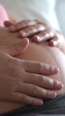 Hamile bir kadın çocuğuna bakarken kendini mutlu hissediyor. Hamile karnında bebek taşıyan hamile bir anne. Doğum öncesi bakım ve kadın hamileliği konsepti.