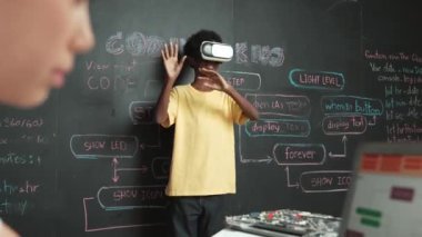 VR kullanan Afrikalı öğrenci meta-dünya ile etkileşime girerken liseli kız el kodlama programını kapat. Zeki çocuk sanal gerçeklik gözlüğü takıyor ve yenilikçi sınıfta video oyunları oynuyor. Öğretim