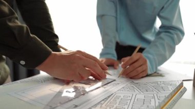 Mimari döküman, ölçüm araçları ve ahşap blokların modern ofiste etrafa saçıldığı masa üzerine planlar yapma konusunda akıllı mimar ve güvenlik mühendisi tartışması. - Yakın çekim. Tanımlama.