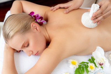 Sıcak bitkisel top spa masaj vücut tedavisi, masör kadın vücuduna nazikçe şifalı bitki torbası bastırıyor. Aromaterapi dinlenme sükuneti ve sükuneti kaplıca salonundaki atmosferi aydınlatıyor. Sessiz.