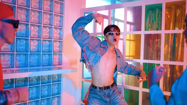 Ortasında dans eden profesyonel mutlu hipster onu alkışlayan çeşitli arkadaşlarıyla dans ediyor. Çekici Asyalı kırığı gece kulübünde neon ışığıyla enerjik adımlar atıyor. Mutluluk.