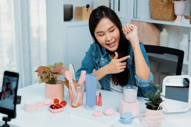 Genç, güzel Asyalı kozmetik makyaj ruju matte pastel rengini modern odadaki sosyal medyada kol testi tanıtımında en çok satanlar listesinde gösteriyor. Taktik.