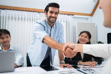 Çeşitli ofis çalışanları stratejik iş pazarlama toplantısı üzerine anlaşma yaptıktan sonra el sıkışıyor. Takım çalışması ve olumlu tutum verimli ve destekleyici bir iş yeri yaratır. Tedbirli