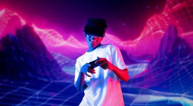 Neon soyut arka planda oyun oynarken elinde joystick tutan ve VR gözlük takan bir genç. Afrikalı adam kontrol etmeyi ve artırılmış gerçeklik teknolojisini kullanmayı seviyor. Yaratıcılık.