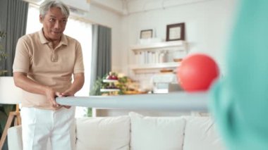 Yaşlı bir adam evde partneriyle top yuvarlama oyunu oynuyor, zihinsel ve fiziksel sağIık için el-göz koordinasyonu, odaklanma ve motor becerileri pratiği yapıyor. Sağlık hizmetleri konseptini engelliyor. Myrmidon.