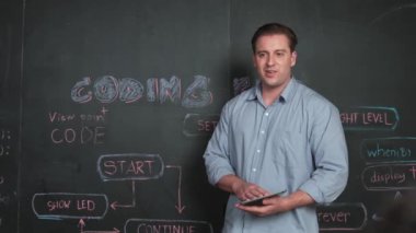 Kodlama programıyla ilgili öğrenci sorusuna beyaz öğretmen cevap veriyor. Beyaz kız, STEM teknoloji sınıfında dizüstü bilgisayar ekranı görüntülerken soru sormak, oy vermek, gönüllü olmak için elini kaldırdı. Öğretim