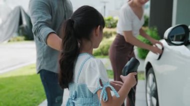 Elektrikli araç şarj istasyonu olan, sağlıklı ve temiz bir çevreyi teşvik eden yenilikçi bir aile kavramı. Sürdürülebilir, temiz enerji teknolojisiyle çalışan elektrikli araç..