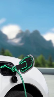 Elektrikli araba, dağ arka planındaki çevre dostu enerji şarj istasyonunun fütüristik akıllı EV şarj cihazıyla şarj oluyor. Sürdürülebilir doğa ve EV arabalı seyahat konsepti. İnceleyin