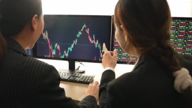Hisse senedi ticareti şirketindeki yavaş hareket eden yatırımcılar, monitörlerde sergilenen borsa pazarlamasında kâr elde ettikten sonra heyecanlanıp kutlama yapıyorlar. Filizlenen