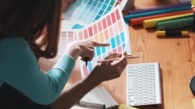 Akıllı tasarımcının renkli paletlerden renk seçmesine yardım ederken yukarıdan aşağı görünümü. Dizüstü bilgisayardan logoya bakarken birlikte çalışan ve planlayan iş adamlarının hava görüntüsü. Sempozyum.