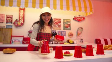 Profesyonel İspanyol restoran işçisi dans ediyor ve yemek barının arkasında duruyor. Kırmızı önlüklü çekici garson kameraya bakarken serbest stil müziğe geçiyor. Çılgın ve komik dans. Mutluluk.