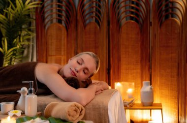 Beyaz kadın müşteri stres önleyici spa masajının keyfini çıkarıyor ve lüks otel ya da otelde sıcak mum ışığında güzellik teniyle eğleniyor. Sessiz.
