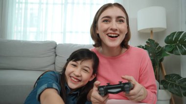 Kafkas anne ve kızı oturma odasında oturup oyun oynuyorlar. Mutlu anne, elinde joystick tutarken akıllı Asyalı kızla vakit geçiriyor. Oyun oynamaktan zevk alıyor. Yaşam tarzı konsepti. Pedagoji.