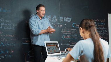 Kafkas öğretmeni alkışlayarak öğrencileri kodlamayı veya programlamayı teşvik etmek için alkışlıyor. Çeşitli öğrenciler STEM sınıfına katılırken başarılı bir projeyi kutlamak için el çırpıyorlar. Öğretim.