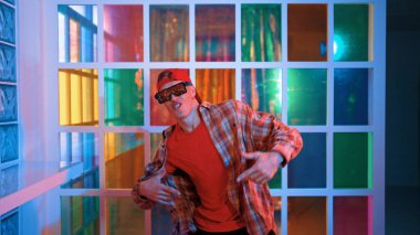 Komik break dansçı kameraya bakarken hiphop 'a doğru serbest adım atıyor. Çılgın mutlu hipster dans edip sokak dansı yaparken Led ışığında günlük kıyafet ve güneş gözlüğü takıyor. Mutluluk.