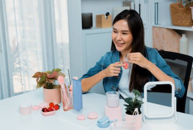 Genç, güzel Asyalı makyaj fırçası yanak testi koleksiyonunu pastel renkle inceliyor. Sosyal medyada akıllı telefonu tanıtmak için pembe ile ışıltılı bir ruh hali sergiliyor. Taktik.