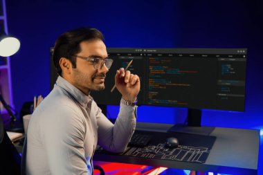 Bilgisayar ekranında yazılım geliştirme kodlu akıllı bilişim geliştiricisi dışarıya bakan bir ekranda poz veriyor, neon ışıklı siber ofiste çevrimiçi web sitesi verilerini sunuyor. Tahmin et..
