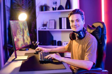 Bilgisayar ekranında muptiplayer ile savaş alanında Moba çalarken kameraya bakan sunucu kanalı konsantre olmuş akıllı oyun flaması. Esport neon odasında canlı yayın yapıyor. Bireysel.