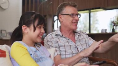 Büyükbaba ve torun birlikte TV 'de ilginç bir eğlence medyası izliyorlar. Eski üst düzey kullanım teknolojisi, genç nesil çapraz nesil ile iletişim kurarak aile bağlarını güçlendiriyor. Uyumsuzluk.