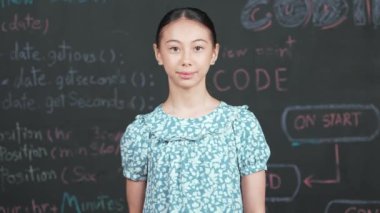 Genç öğrenci başarılı projesini kutlarken kolunu kaldırdı. Mühendislik koduyla karatahtaya bakarken kameraya bakan mutlu genç, STEM sınıfında yazılı. Öğretim