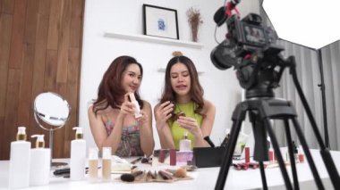İki kadın nüfuzlu partner sosyal medya veya blog için canlı yayın yapan video klip inceleme derisi çekiyorlar. Canlı kozmetik stüdyo ışığı olan genç bir kız çevrimiçi pazarlama kayıt oturumu yayını için.