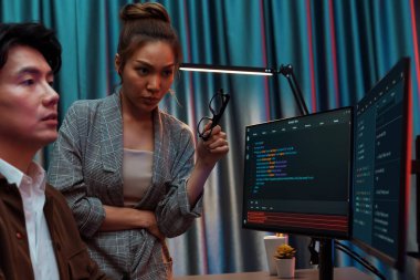 Bilgi teknolojisi geliştiricileri modern ofisteki neon ışık odasında verileri çevrimiçi olarak çalıştıran akıllı web sitesi geliştirme kodlayıcı sistemine işaret ediyorlar. İnfobahn.