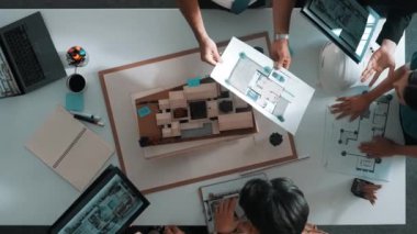 Yöneticinin ev modelini göstermesi ve bina tasarımını açıklaması. Tablet ev planı sergilenirken iç yapı hakkında beyin fırtınası yapan mimar mühendisinin hava görüntüsü. Hizalama.