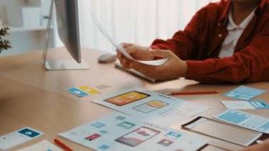 Mobil uygulama için kullanıcı arayüzü prototipini ofis çalışanlarına sunan harika bir şirket çalışanı. UX UI tasarımcısı kağıt üzerinde simge tasarımının işlevini açıklıyor. Sinerjik