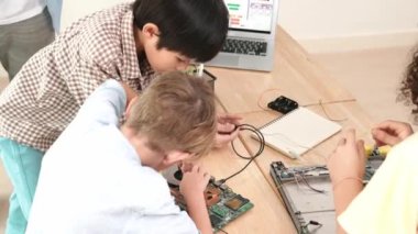 Öğretmenler tableti tutarken ve BTMM teknoloji sınıfında çevrimiçi yazılımı açıklarken ana ekranda dizüstü bilgisayar mühendisliği komut yazısıyla birlikte çalışan çeşitli öğrenci grubu. Pedagoji.