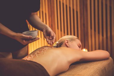 Lüks spa salonlarında sıcak mum ışığında cilt bakımı yaptıran kadın müşteri. Sağlık Spa vücut fırçasında tuz temizleme güzellik tedavisi. Sessiz.