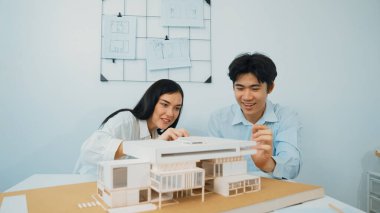 Mimari belge ve ev modeli ile toplantı masasının üzerindeki ev modelini ölçerek birlikte çalışan profesyonel mimar ekibinin yakın plan görüntüsü. Yaratıcı tasarım konsepti. Tertemiz..