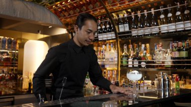 Asyalı barmen karışık kremalı votka bardağı servis ediyor. Önünde buzlu pembe çiçekli şeker, önünde özel içecek, lüks tezgah barında alkolü canlandırıyor. Vinosity.