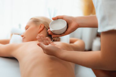Masör elleri kadının sırtına aroma yağı döküyor. Masözler lüks otellerdeki kaplıca salonundaki müşteriler için yağ masajı prosedürü hazırlıyorlar. Aroma yağı vücut masajı konsepti. Sessiz.