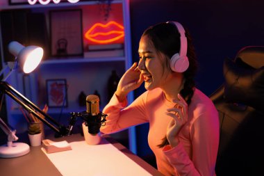 Geceleri podcast 'te olumlu konuşmalar yapan, pembe neon ışıklı modern stüdyoda sunum için dizüstü bilgisayar kullanan, gülümseyen, genç, güzel Asyalı bir etkileyiciydi. Taktik.