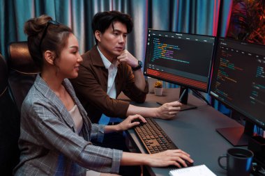 Bilgi teknolojisi geliştiricileri modern ofisteki neon ışık odasında verileri çevrimiçi olarak çalıştıran akıllı web sitesi geliştirme kodlayıcı sistemine işaret ediyorlar. İnfobahn.